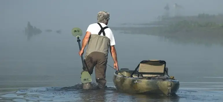 Fisherman walking with Kayak in Water